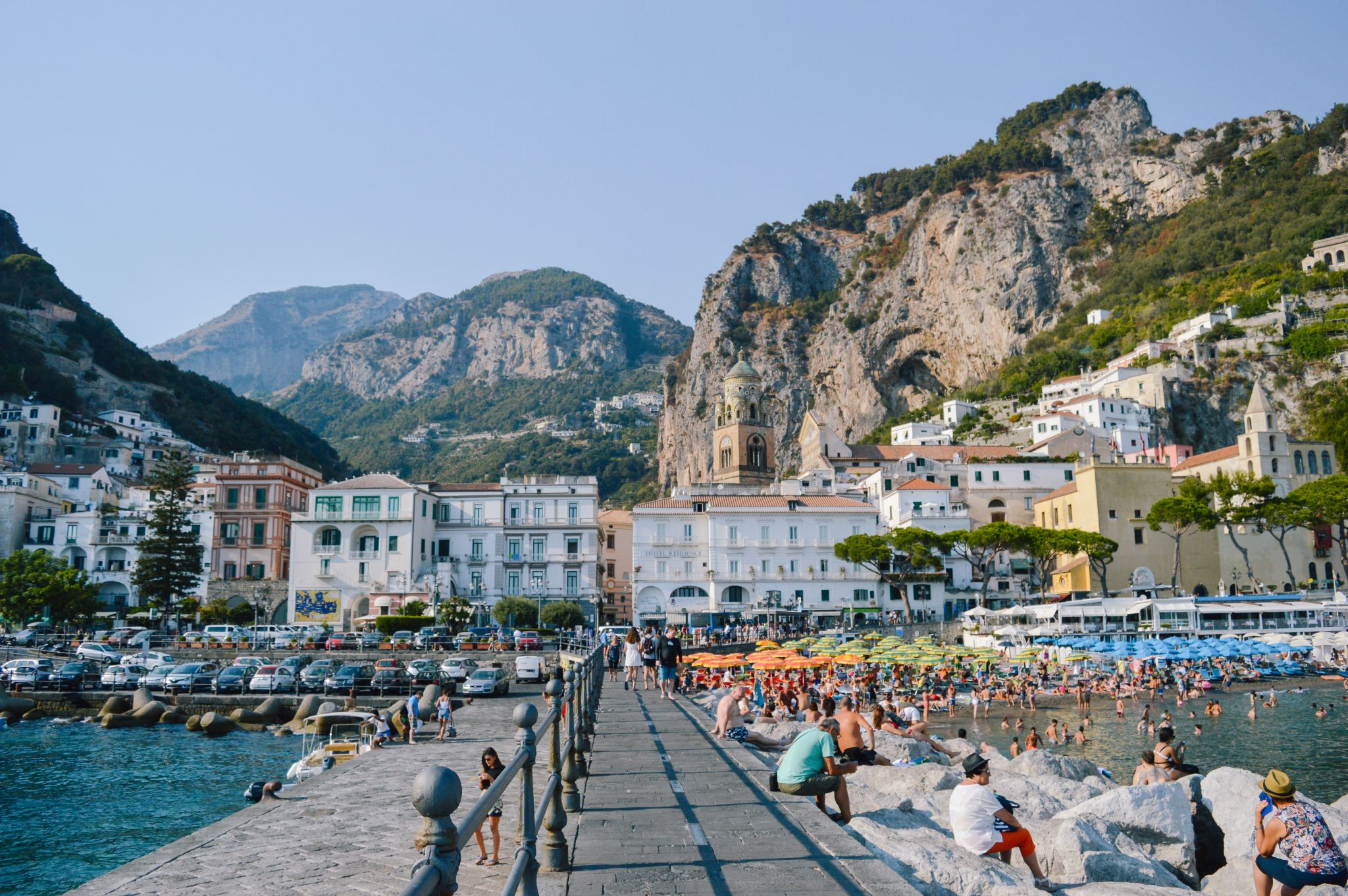 Turisti, bagnanti, ombrelloni colorati, macchine parcheggiate, paesino nella Costiera Amalfitana, Campania